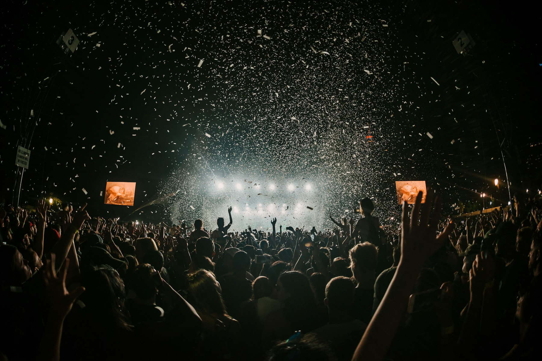 Festival crowd under falling confetti and stage lights